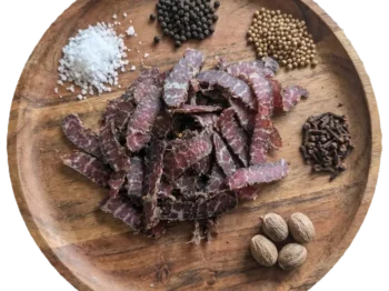 Biltong Snacks with spice ingredients on a wooden platter.