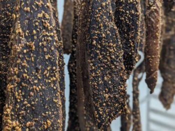Dried Natural Biltong slab hanging for air curing in a traditional meat drying room.