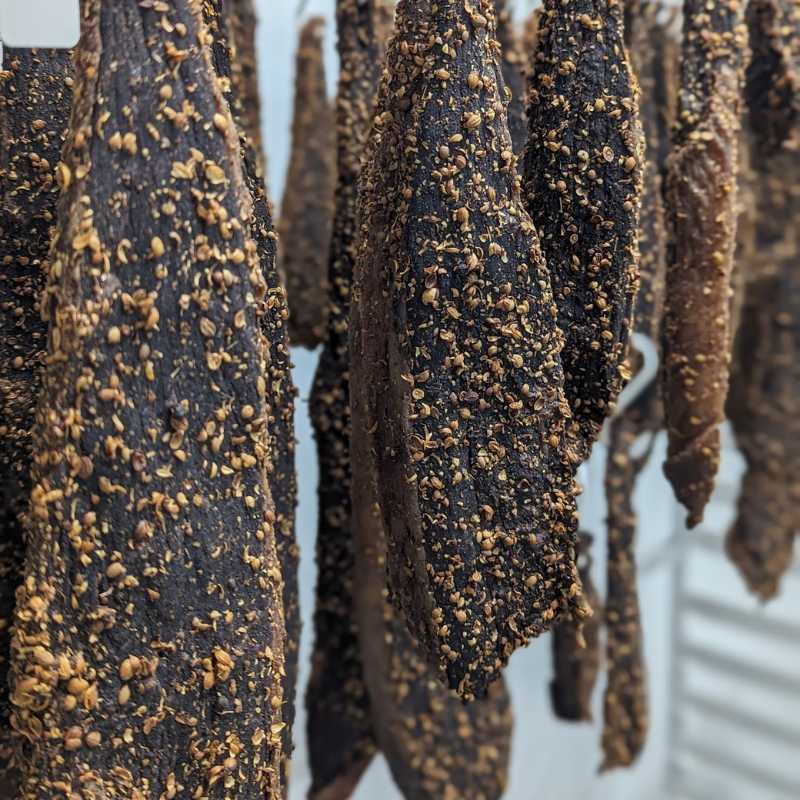 Dried natural biltong slab hanging for air curing in a traditional meat drying room.