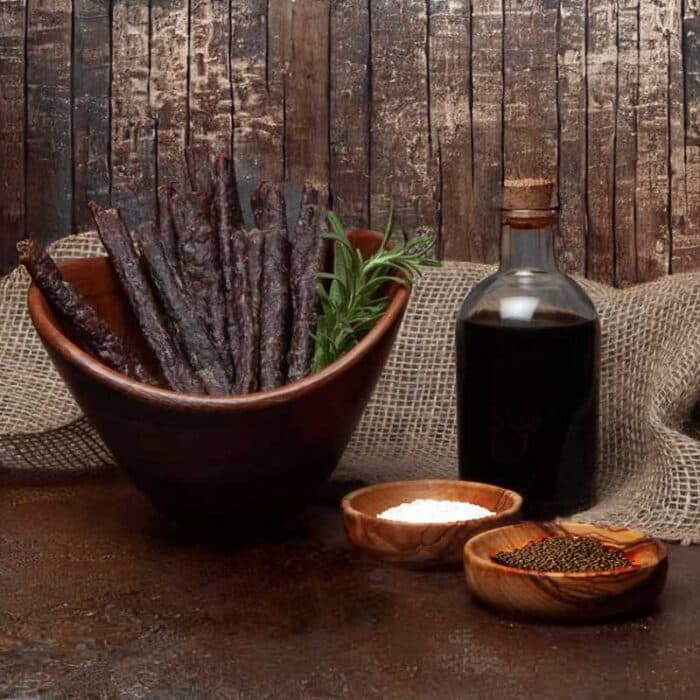 A bowl of natural meatsticks/droëwors and a bottle of vinegar