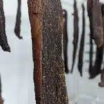 a close up of biltong hanging from a rack