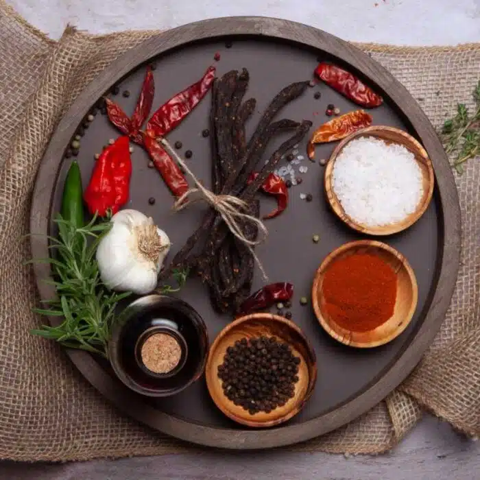 A round wooden tray with various spices,chilibites and herbs