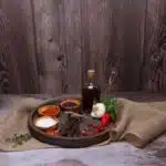 a round wooden plate with chilibites, spices and herbs on it