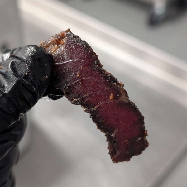 A hand holding high protein snacks, such as biltong slices