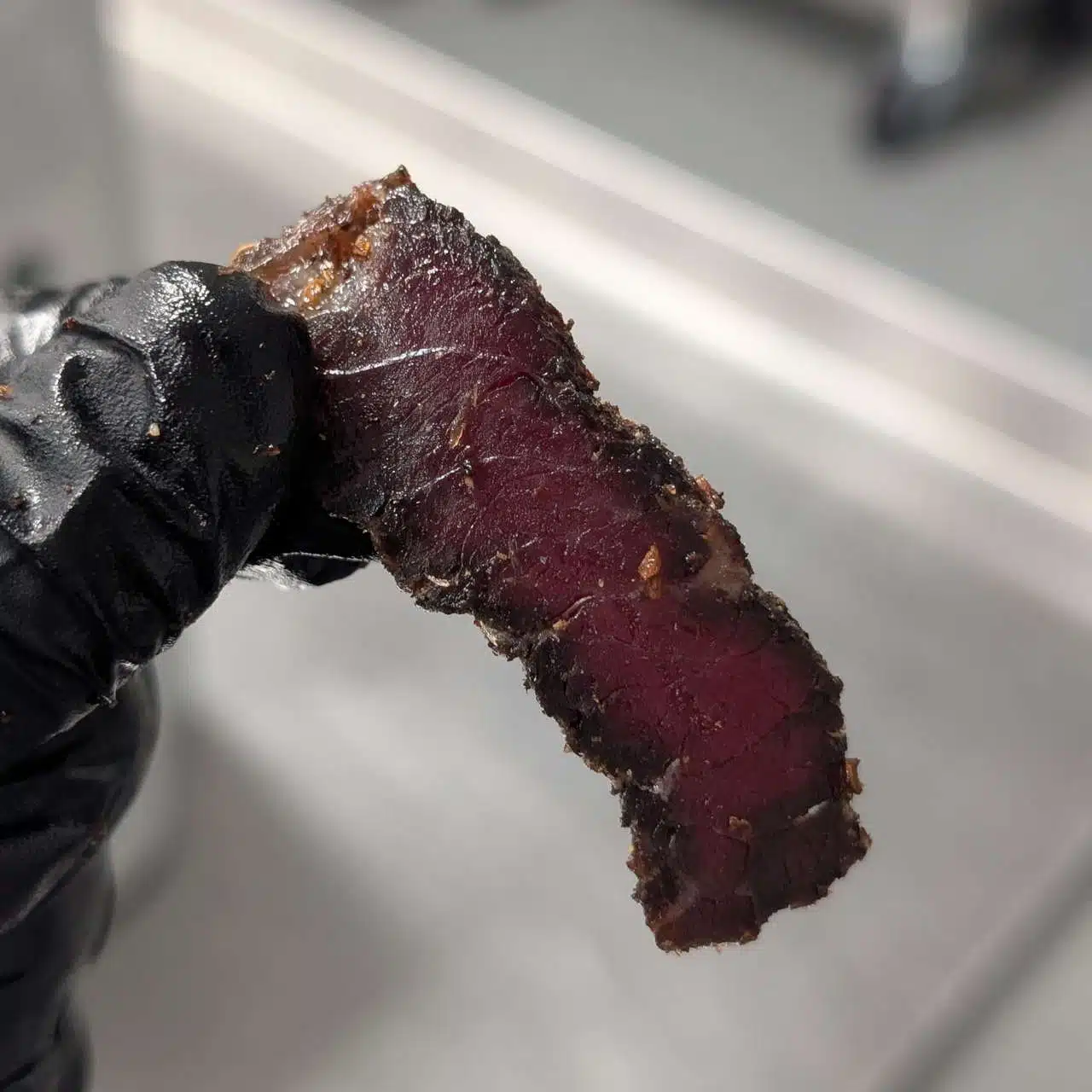 A hand holding high protein snacks, such as biltong slices