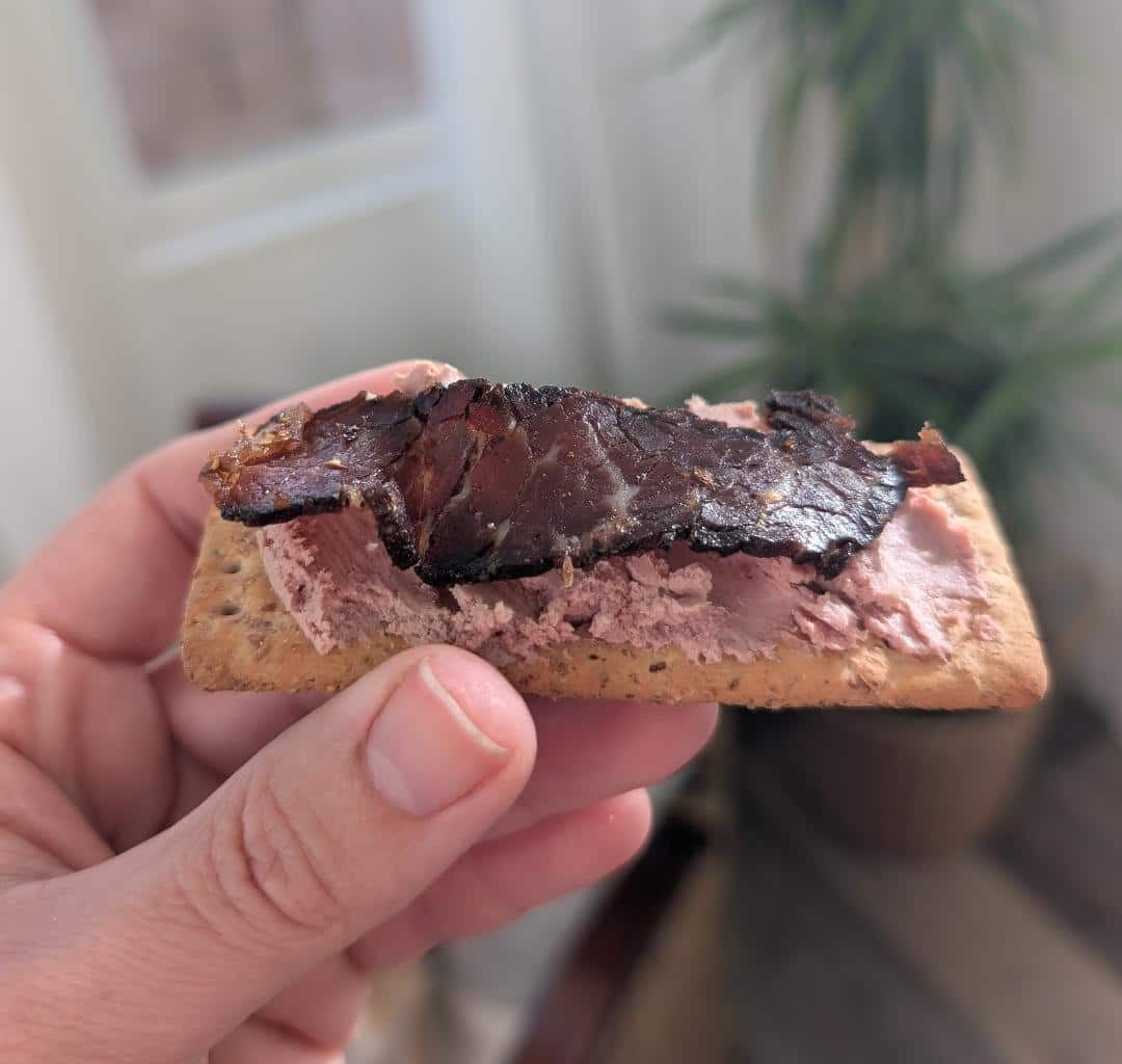 A slice of biltong protein snacks on top of pate and a wholewheat cracker