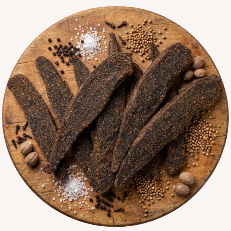Biltong Slabs on a round wooden platter with spices.