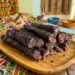 Traditional South African droëwors sausages on wooden platter with colorful African fabric background.