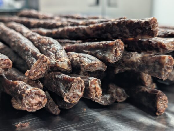 Close-up of dried beef sticks with glossy texture and rich brown color.