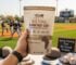 Hand holding YEBO Biltong beef snack at sunny baseball field during spring training.