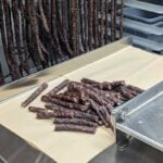 Beef jerky production line with dried meat sticks being cut and prepared for packaging.