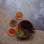 Rustic beef jerky with assorted spices on burlap cloth and wooden bowls.